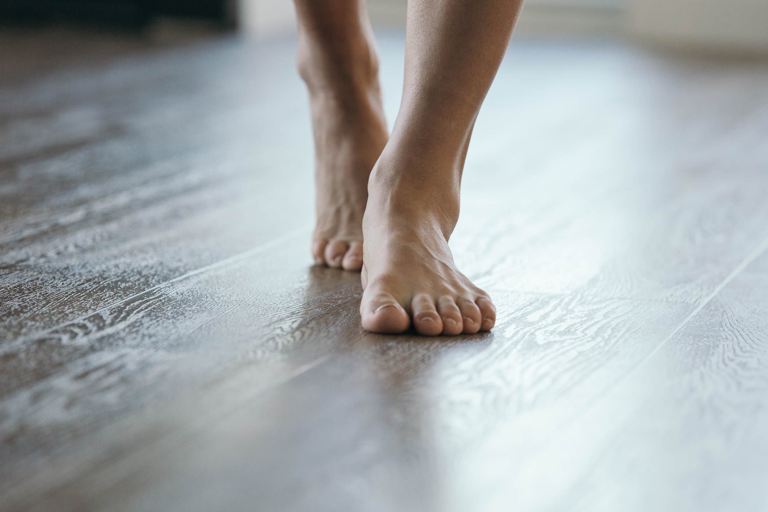 Bare feet on warm hardwood floor in a luxurious home, illustrating radiant floor heating comfort