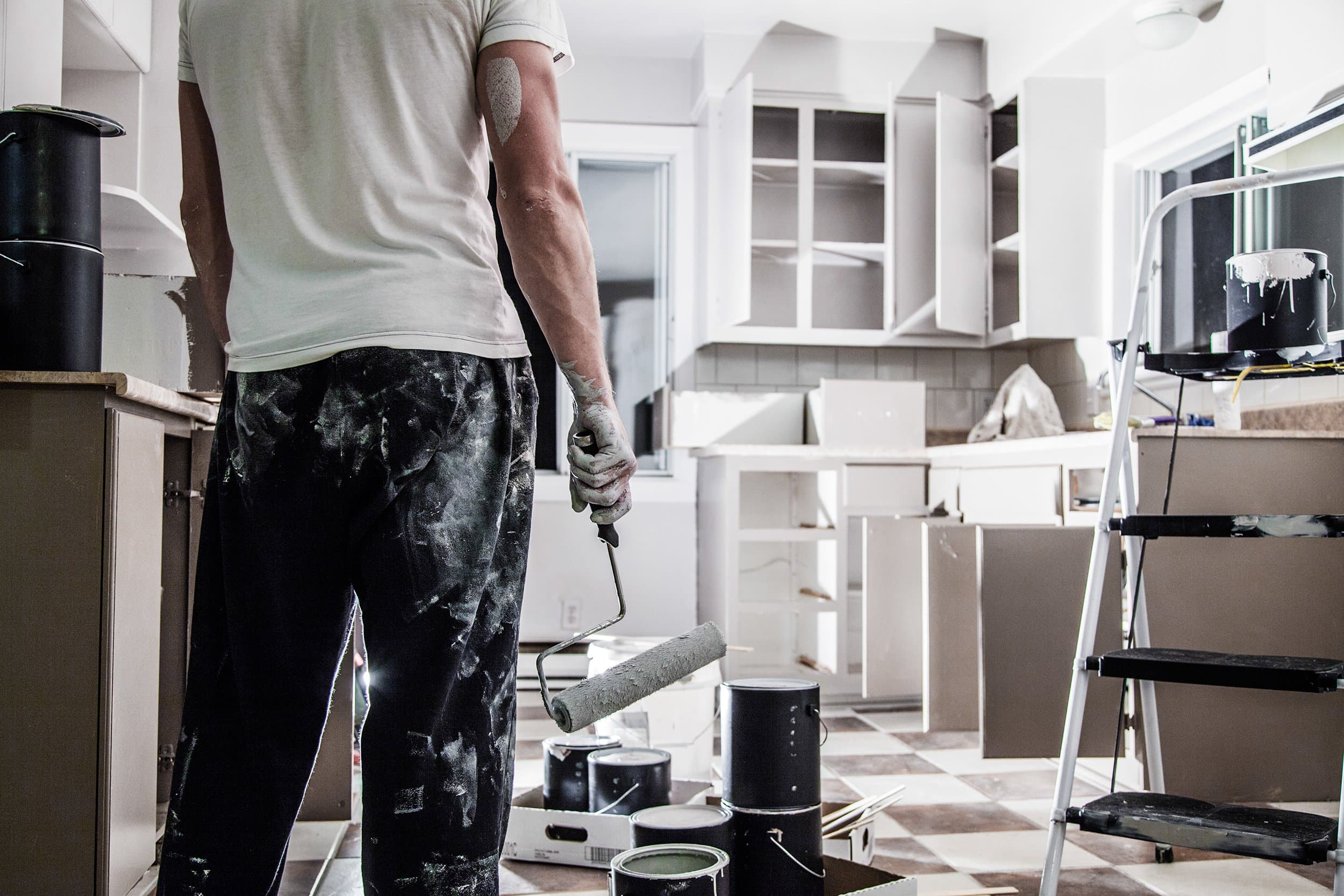 Stressed homeowner reviewing paperwork while coordinating multiple contractors working throughout a luxury home
