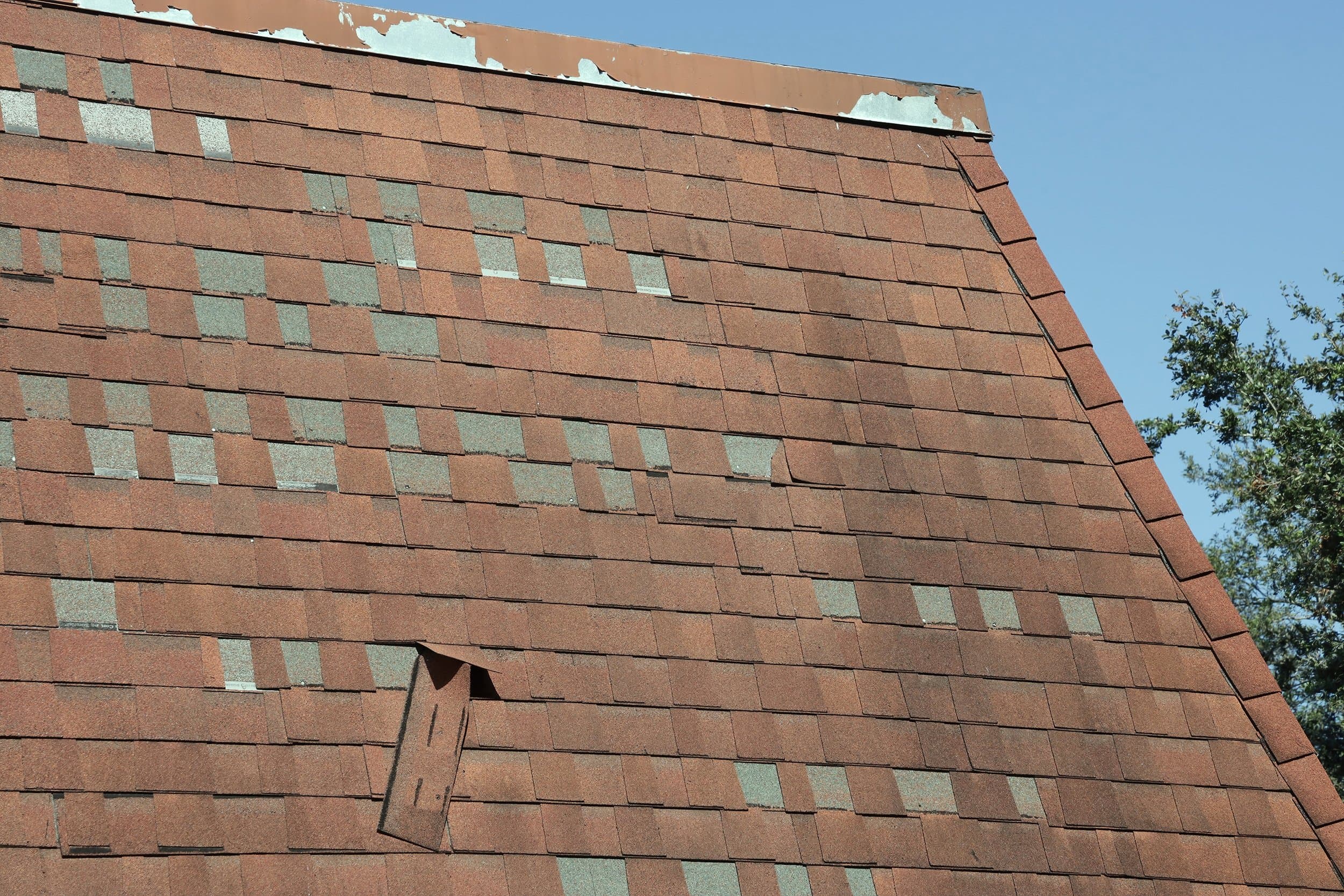Homeowner inspecting exterior walls and roofline of a Boulder house for winter damage on a clear spring day