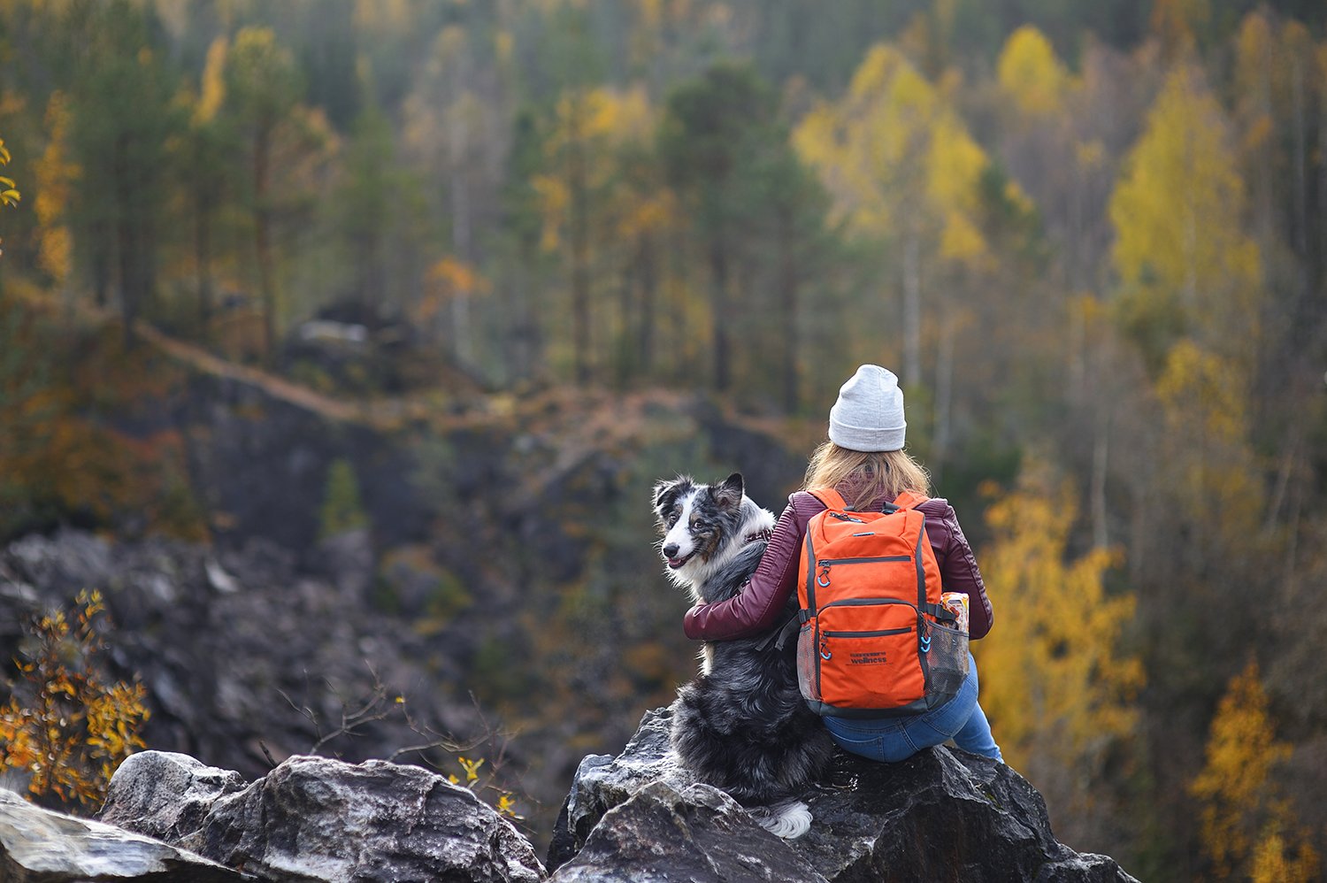   A woman holds onto her dog while resting on a fall hike. Looking for the best dog-friendly hikes in Boulder? Check out our Ultimate Guide on Boulder Hikes and discover your next best hike with your dog.  