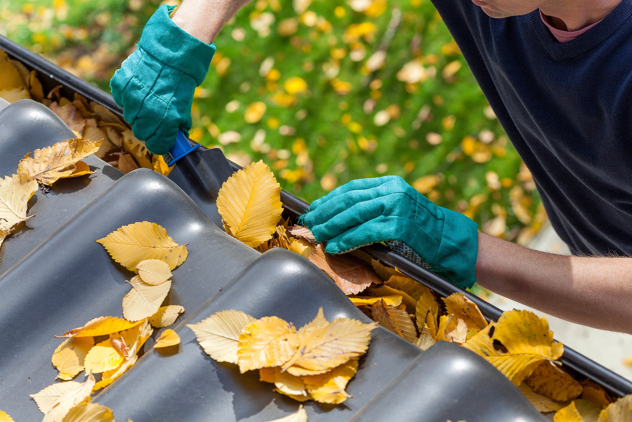  A person cleans out gutter debris in the fall. Winter home prep completed in the fall can be a huge step in minimizing damage to a guest home. 