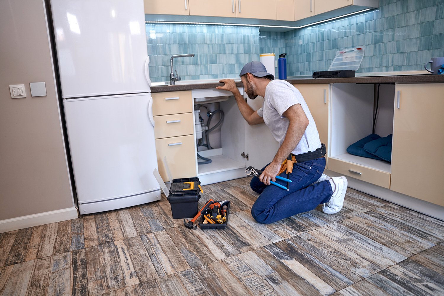  A professional handyman inspects the plumbing underneath a sink. Learn when to call for professional help when pipes may show evidence of freezing and how a home concierge can help.  